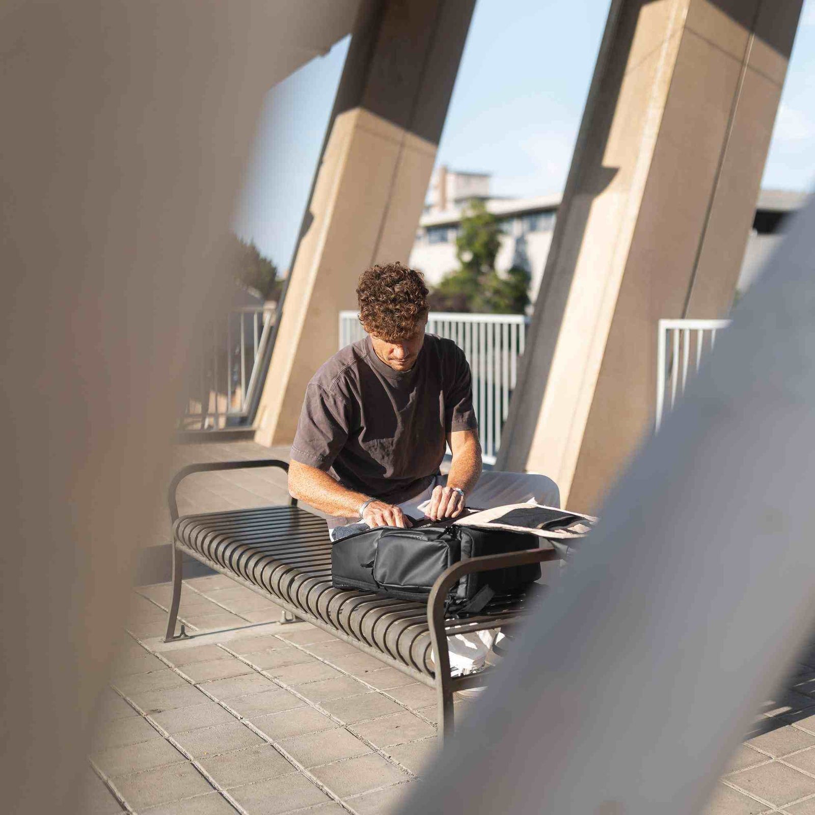 Mann sitzt draußen auf einer Bank und benutzt einen Laptop