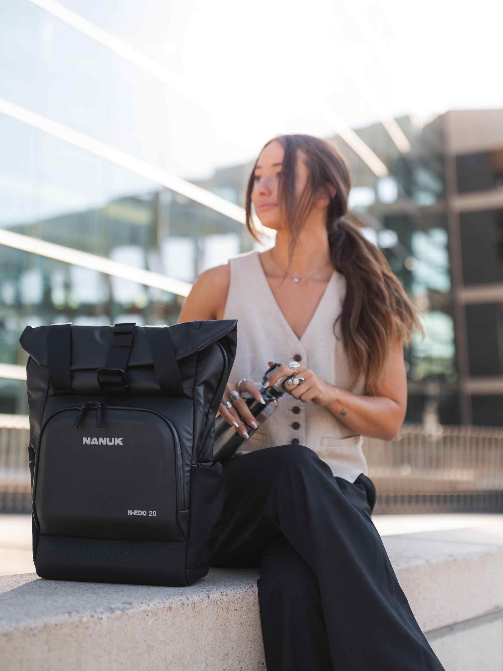 Frau sitzt mit einem schwarzen Nanuk-Rucksack in einer städtischen Umgebung