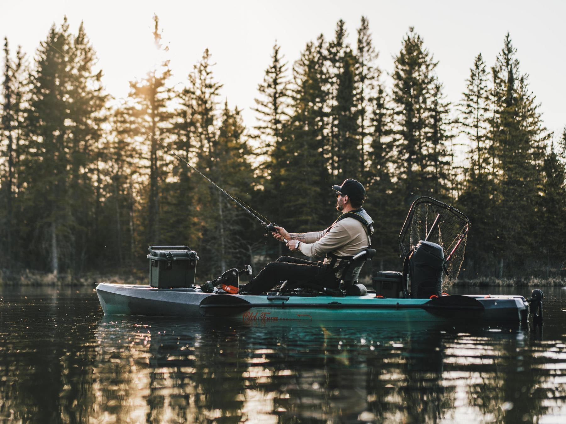 Man fishing from a boat on a lake with trees in the background
