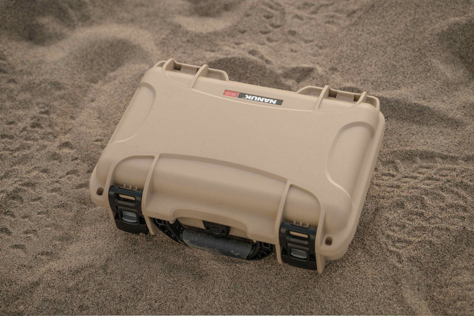 Die schützende NANUK 909 Hard valise in sandiger Umgebung, die ihre Zuverlässigkeit im Freien unter Beweis stellt.