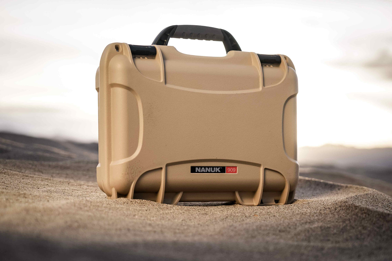 Robuste NANUK 909 Hard valise in hellbraun, gebaut um extremen Bedingungen standzuhalten, ausgestellt auf einem Wüstengelände.
