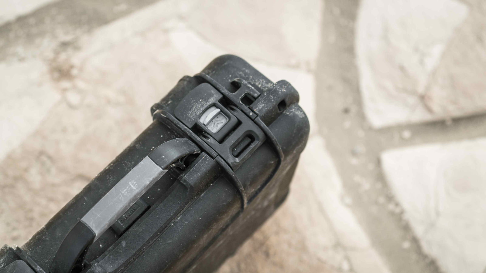 Black NANUK 910 hard case with a sturdy handle, sitting on a rustic wooden surface, perfect for protective gear storage.