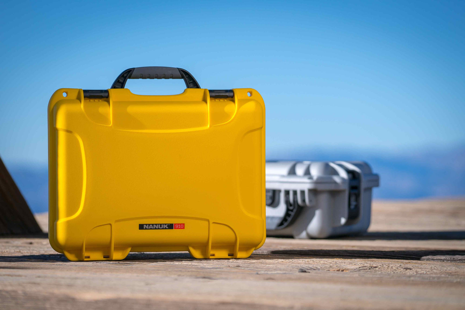 NANUK 910 yellow hard case displayed on a wooden floor, showcasing its rugged exterior for ultimate protection.