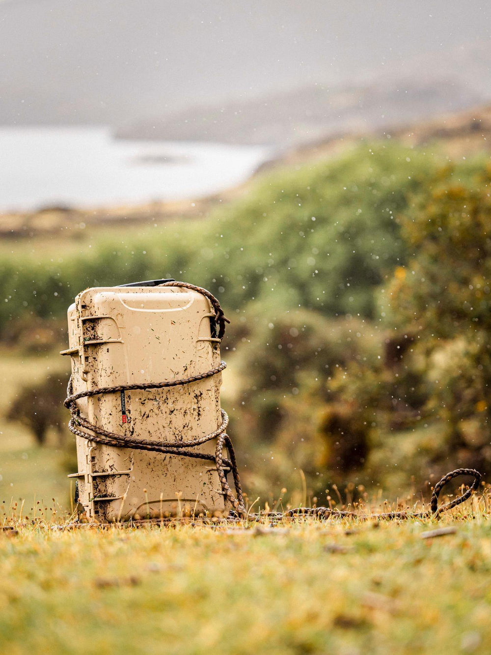 Mud-covered cooler in a grassy field with a blurred background