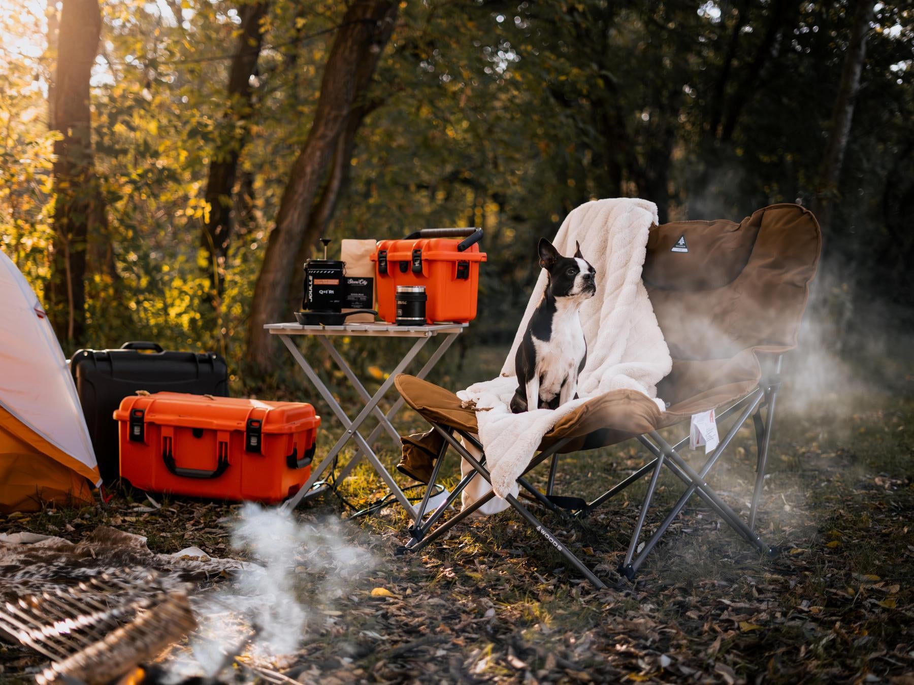 Camping scene with a chair, table, and camping gear in a forest setting.