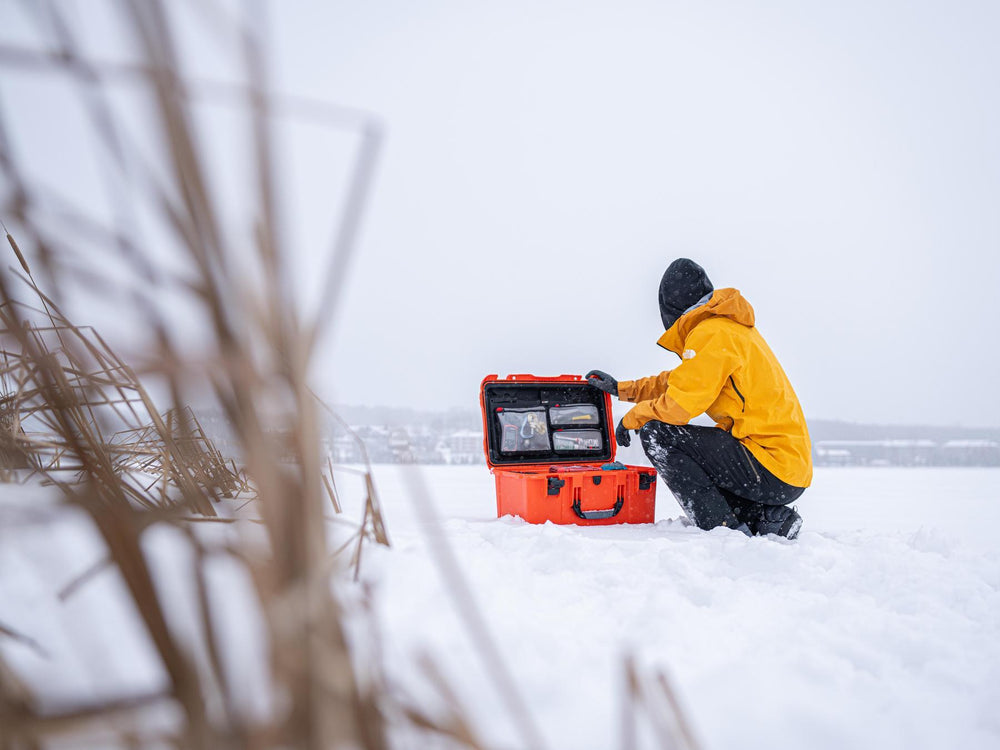 Person in yellow jacket with equipment in snowy landscape