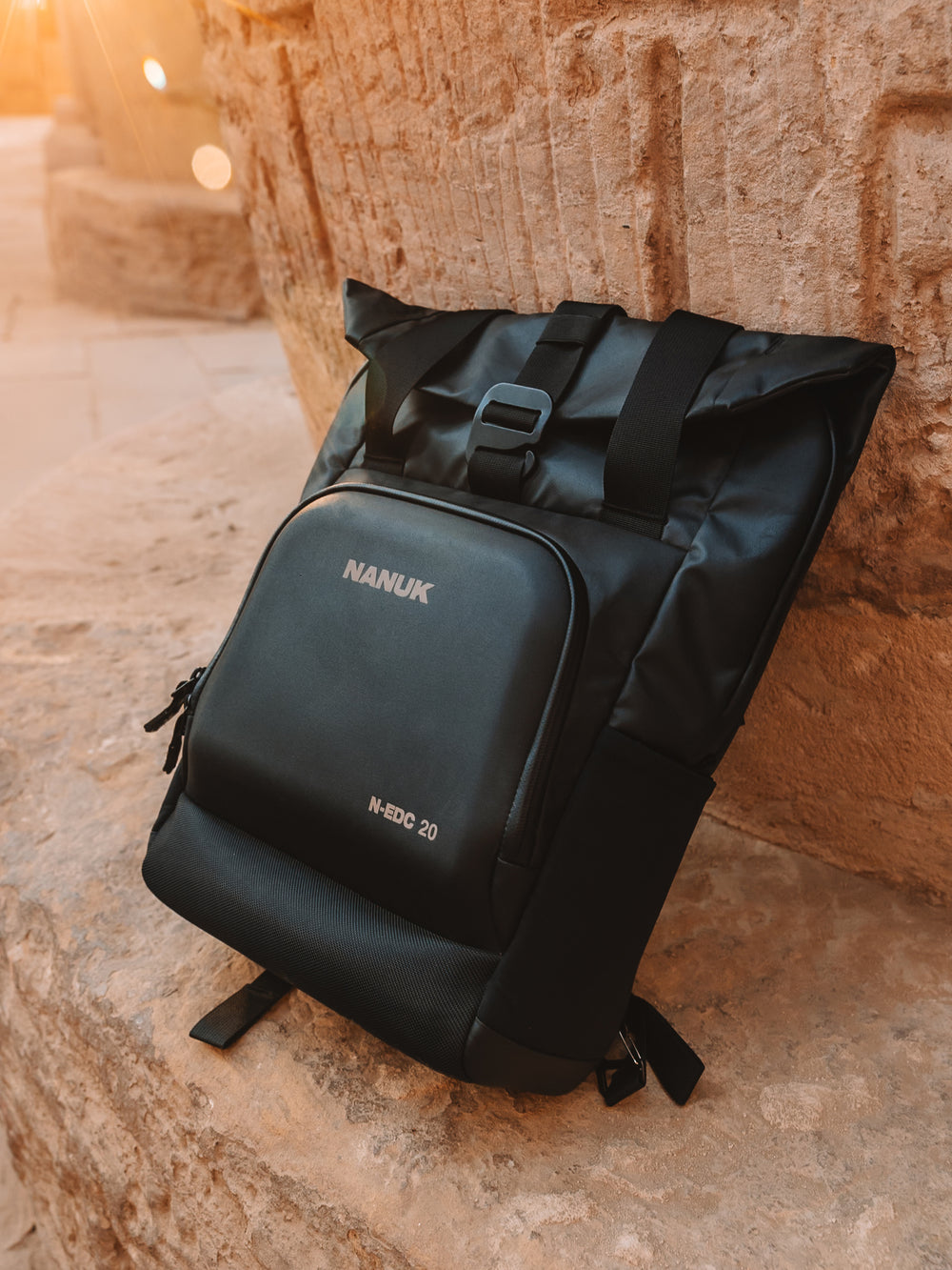 Black backpack with 'NANUK' branding on a stone surface