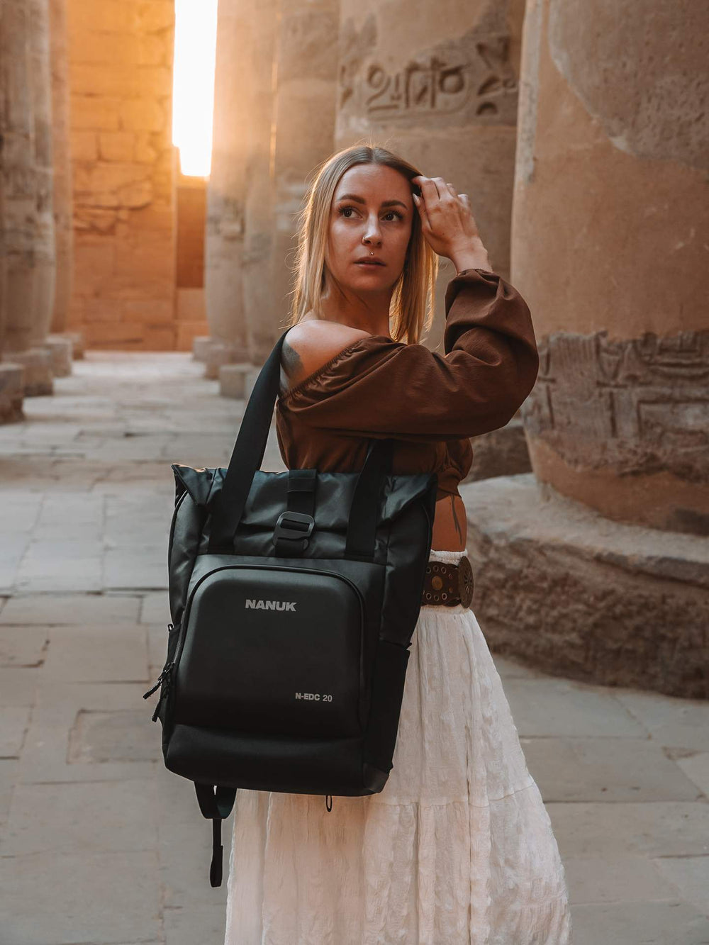 Woman holding a black backpack with 'KARL' branding in an ancient temple setting