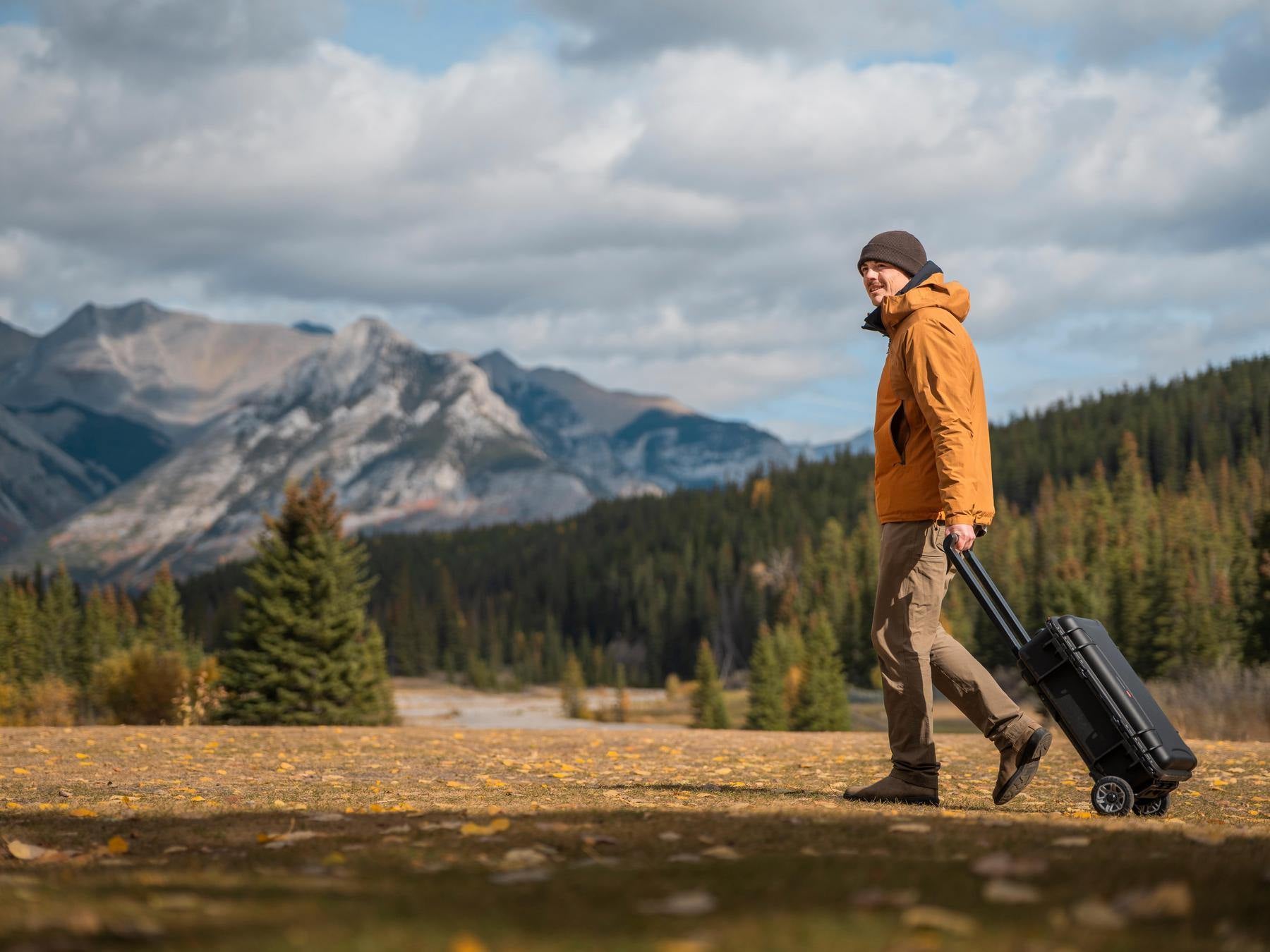 Person walking with a suitcase in a mountainous landscape