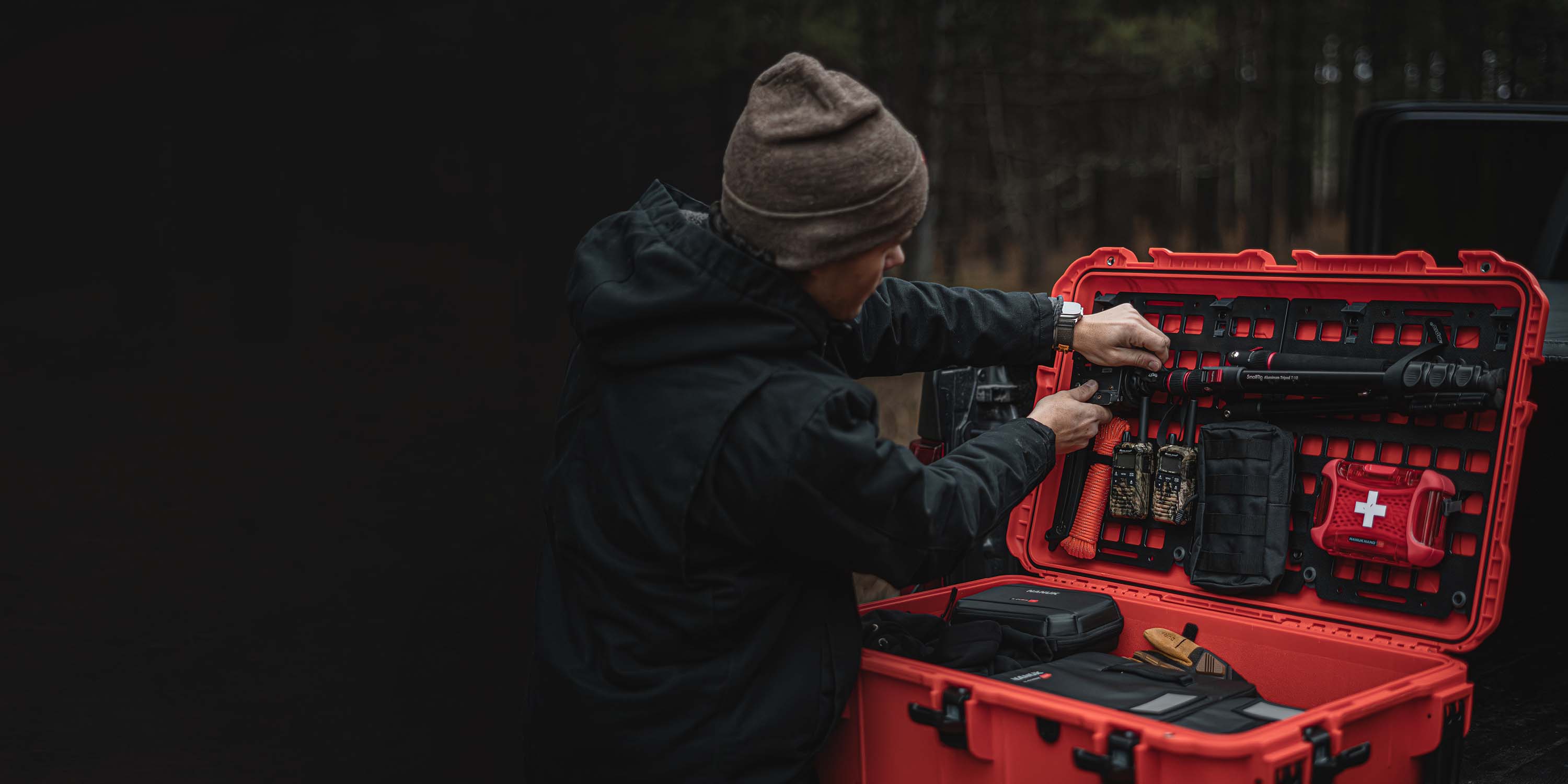 Outdoor-Enthusiast, der seine taktische Ausrüstung in einer roten valise mit individuellem Deckel-Organizer und Erste-Hilfe-Material anpasst.