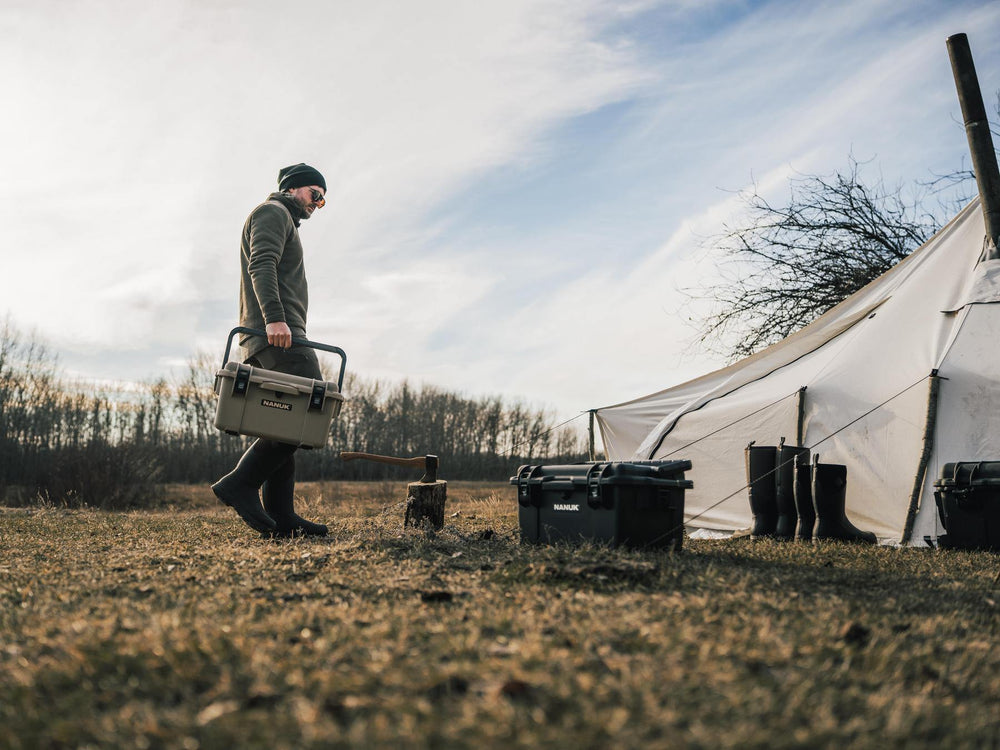 Person with a toolbox near a tent in an outdoor setting