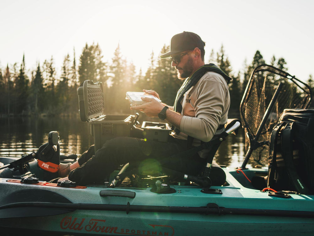 Man on a kayak by a lake with trees in the background