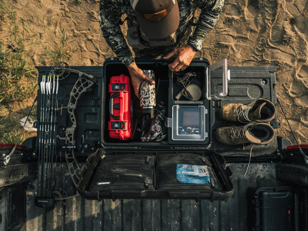 Person organizing items in a black toolbox outdoors