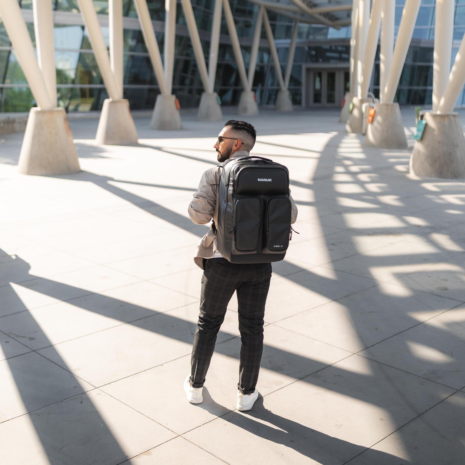 Mann mit Rucksack vor modernem architektonischem Hintergrund