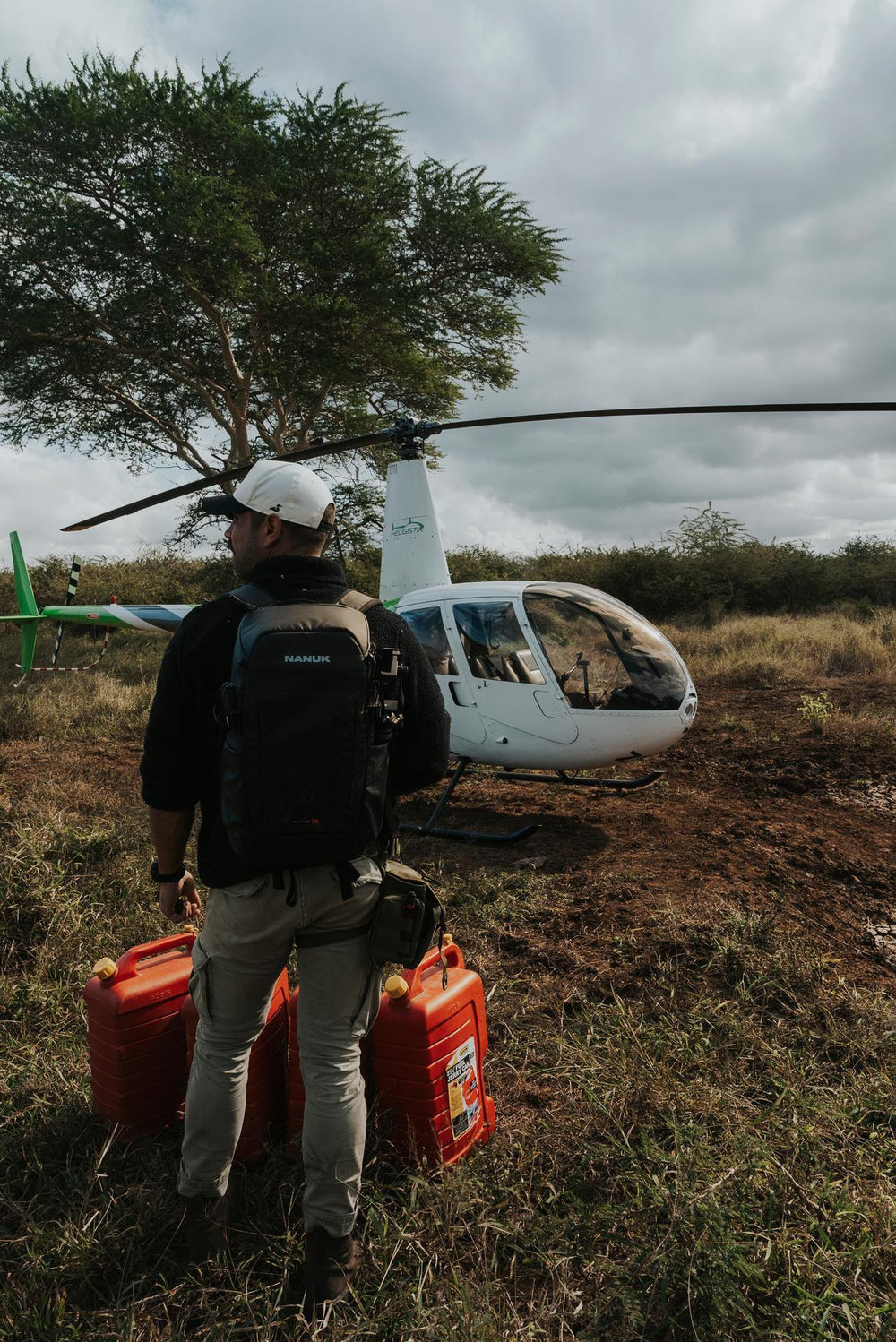 Person with supplies walking towards a helicopter in a natural setting