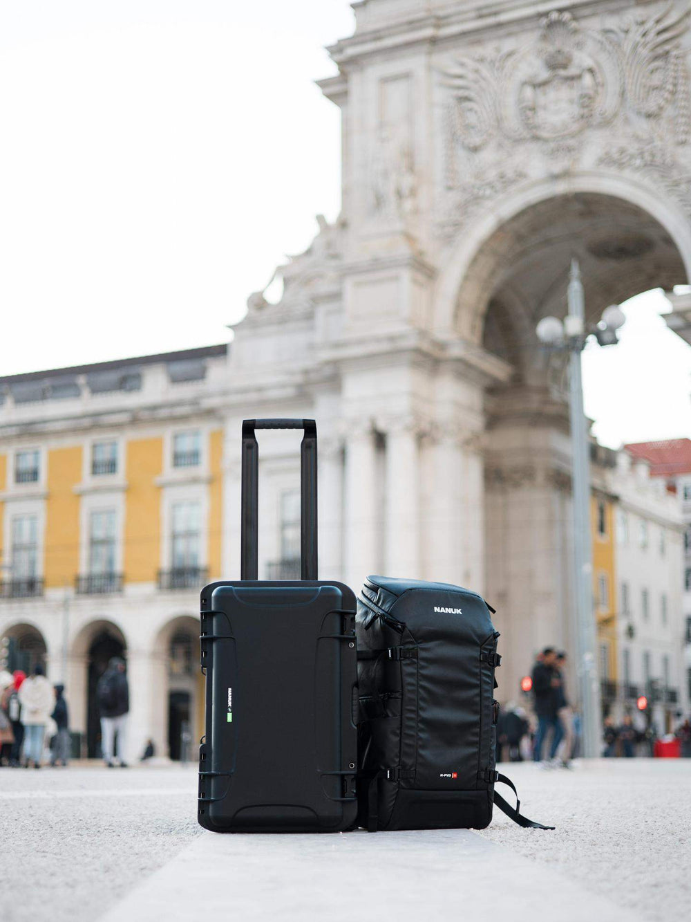 Two black suitcases in front of a large archway in an urban setting