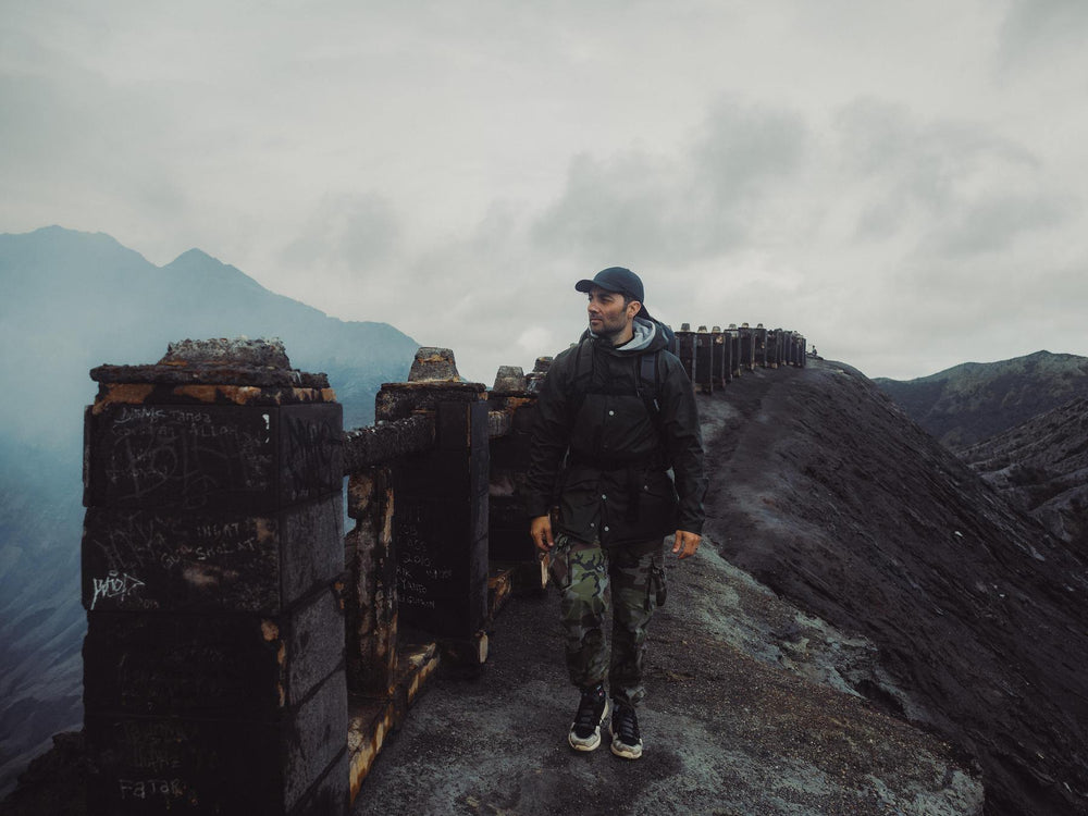 Person standing on a mountainous landscape with a cloudy sky