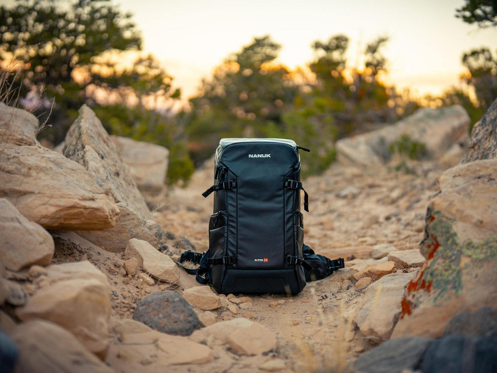 Black backpack on a rocky landscape with trees in the background
