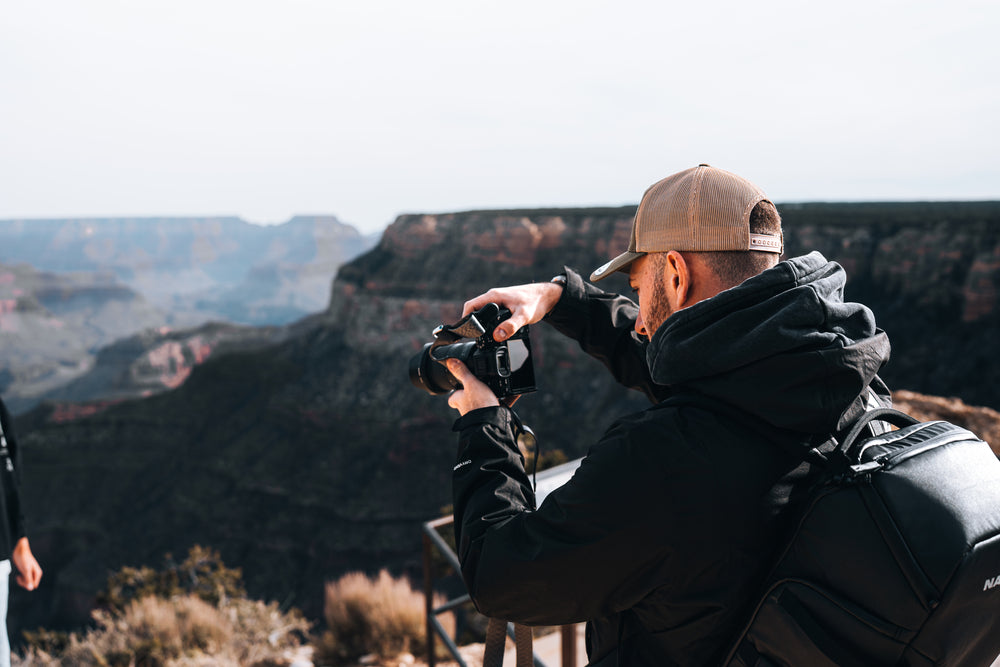 Person taking a photograph of a scenic landscape with mountains in the background