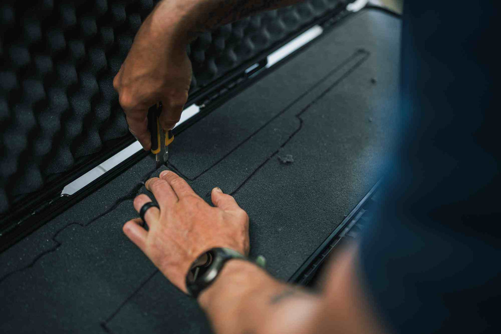 Eine Person, die mit einem Werkzeug an einer schwarzen Oberfläche arbeitet