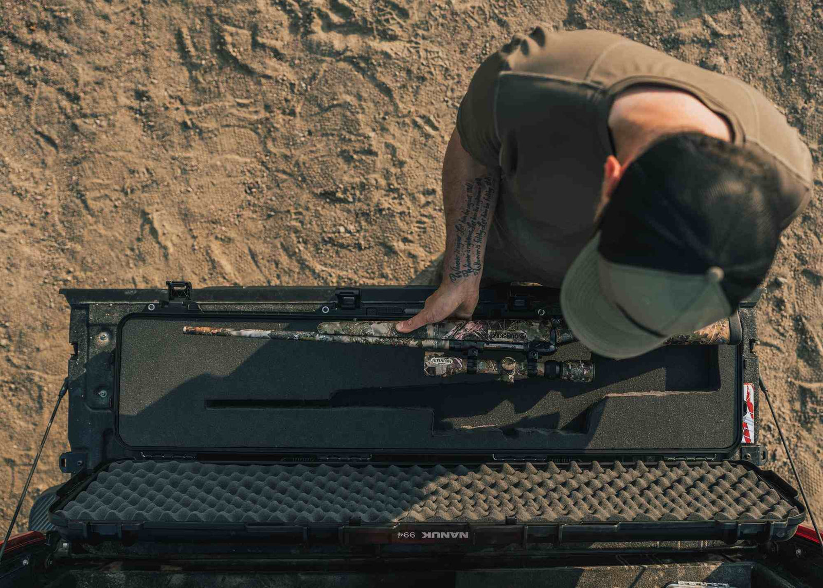 Eine Person, die draußen Gegenstände in einem großen schwarzen Koffer verstaut.