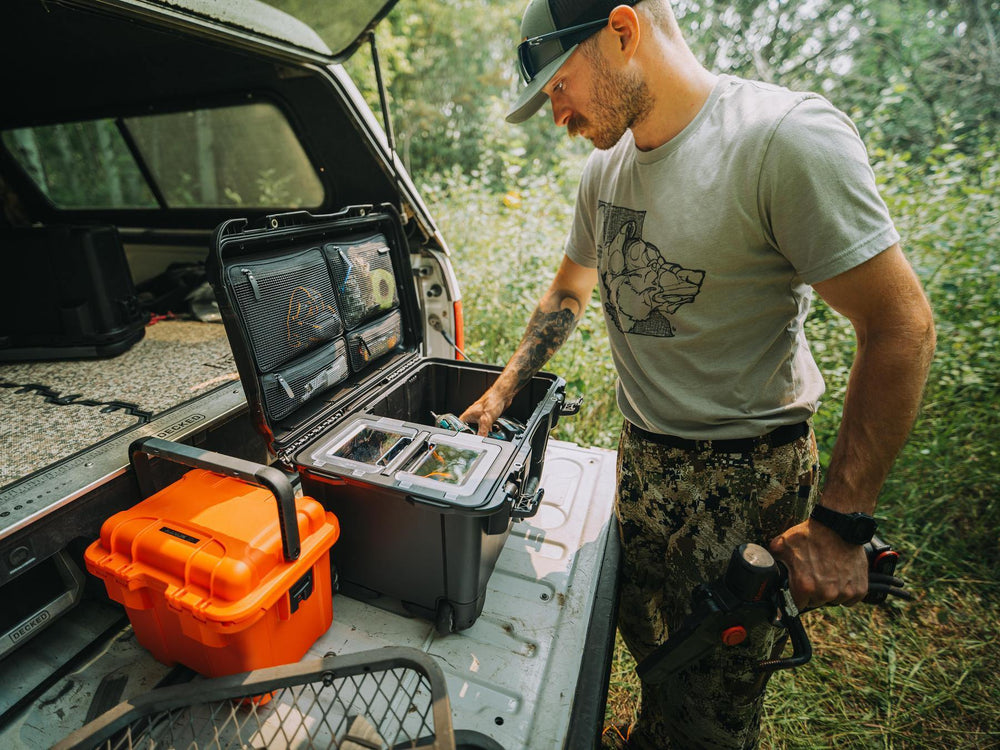 Man in outdoor setting with open toolbox and orange cooler