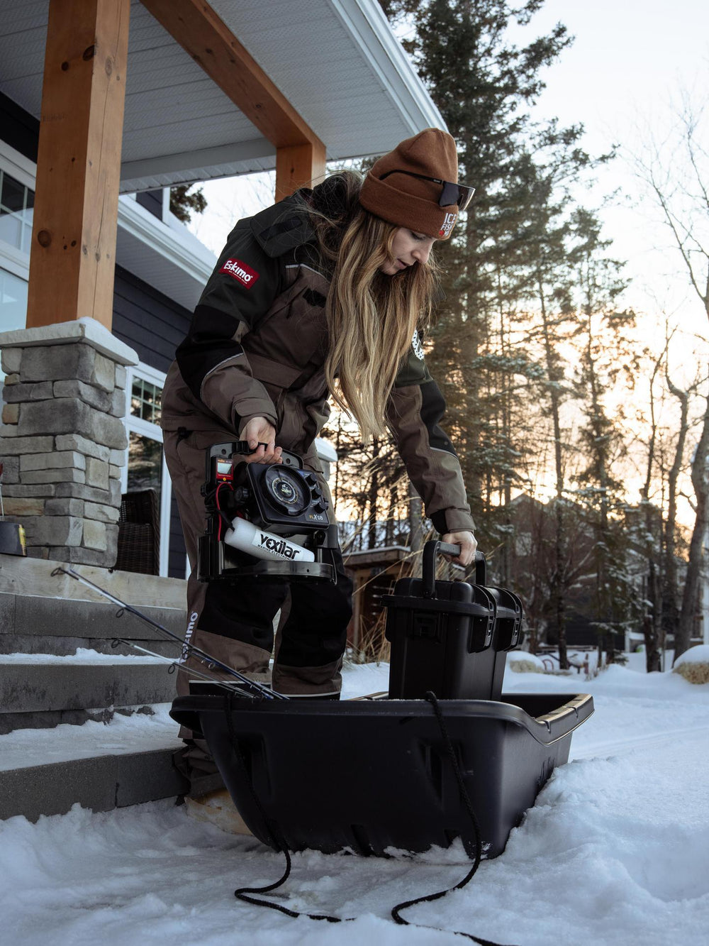 Person using a snowmobile starter machine on a snowy porch