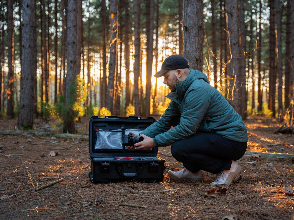 Person in a forest setting using a device from a black case