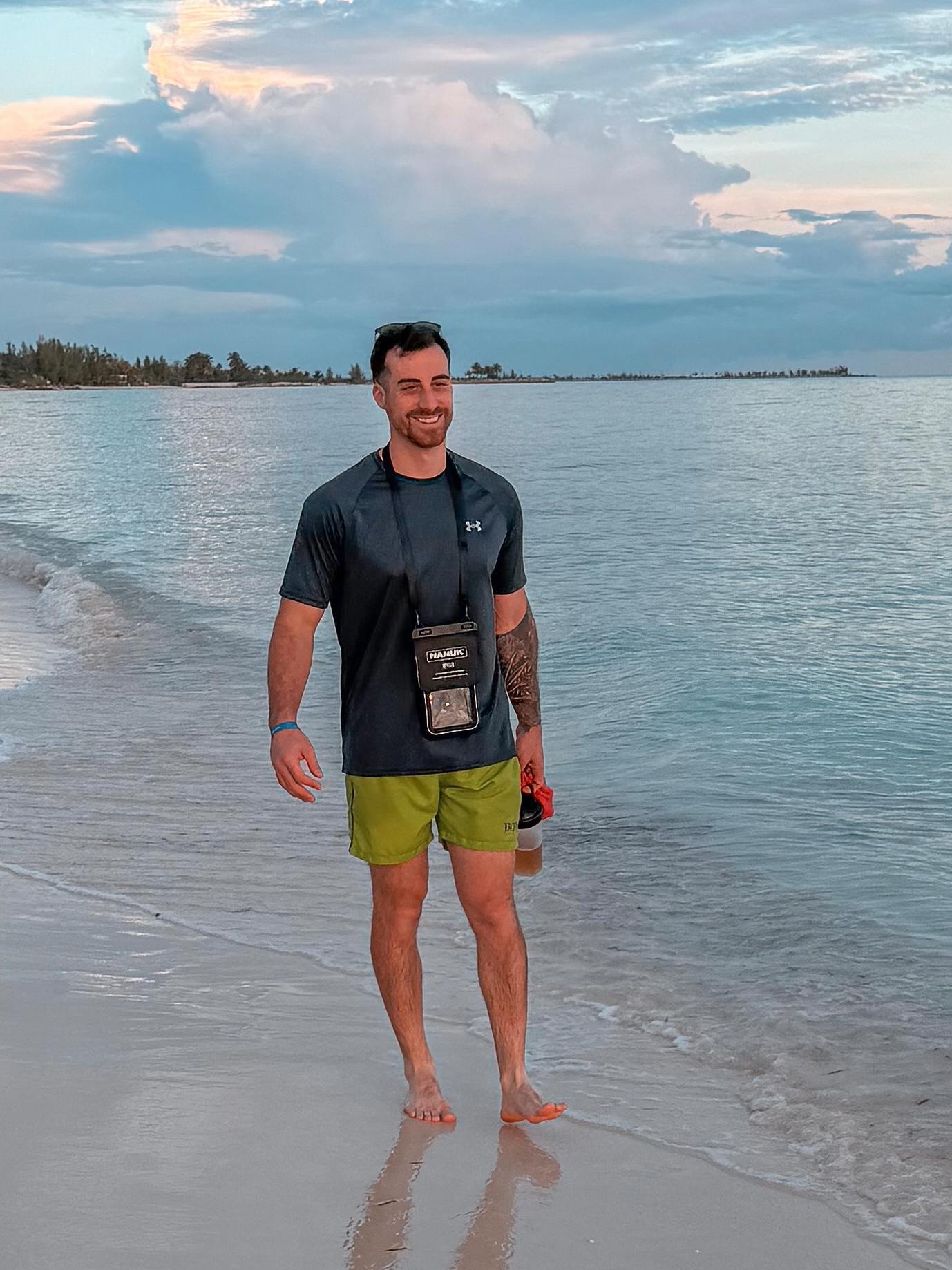 Ein Mann steht am Strand vor einem malerischen Hintergrund aus Himmel und Wasser